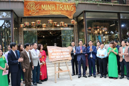 Các đại biểu gắn biển điểm dịch vụ du lịch thân thiện với môi trường tại cửa hàng Thêu Minh Trang.